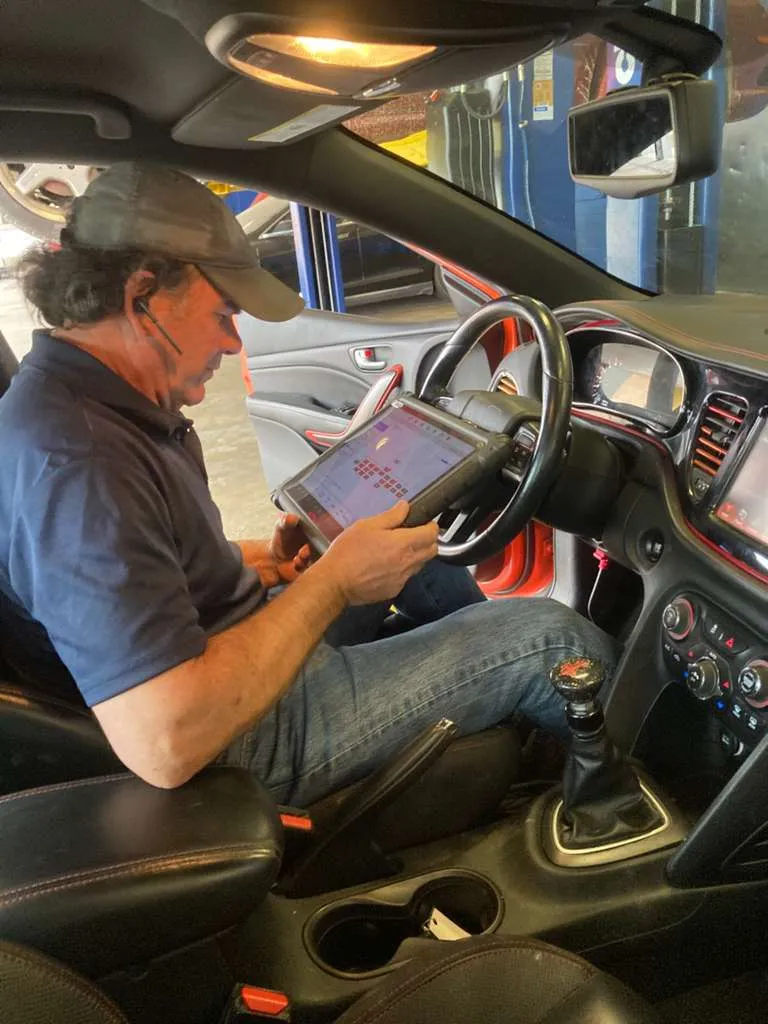 Technician using a tablet for internal auto repair diagnostics.