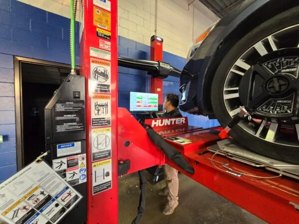 Professional technician performing a wheel alignment at an auto repair shop using Hunter engineering equipment.