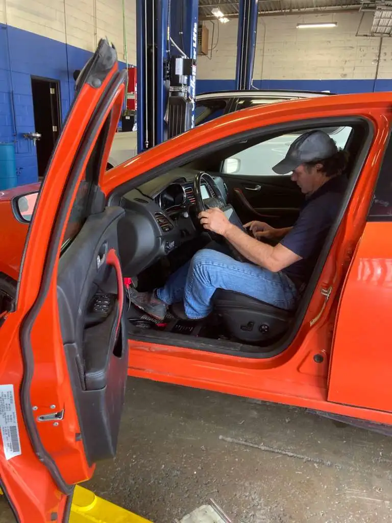 Professional technician using a digital scanner for car computer diagnostics at an auto repair shop