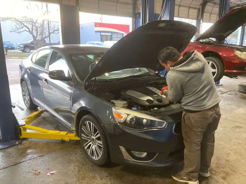 Auto repair technician working on a modern GDI car engine.