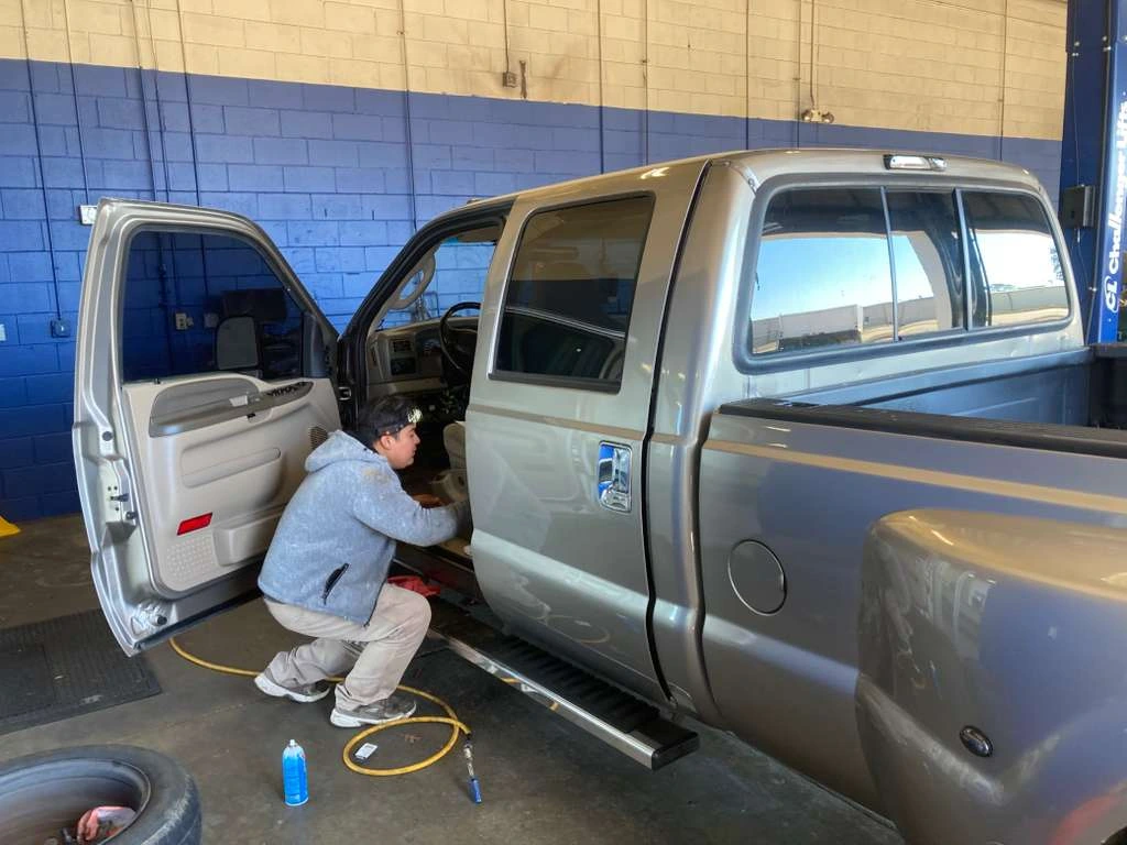 Professional technician performing interior seat repair or electrical maintenance on a truck at an auto repair shop